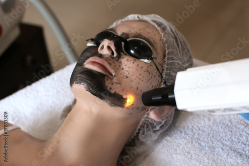 Young woman undergoing carbon peeling procedure in salon