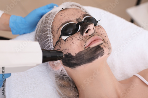 Young woman undergoing carbon peeling procedure in salon photo