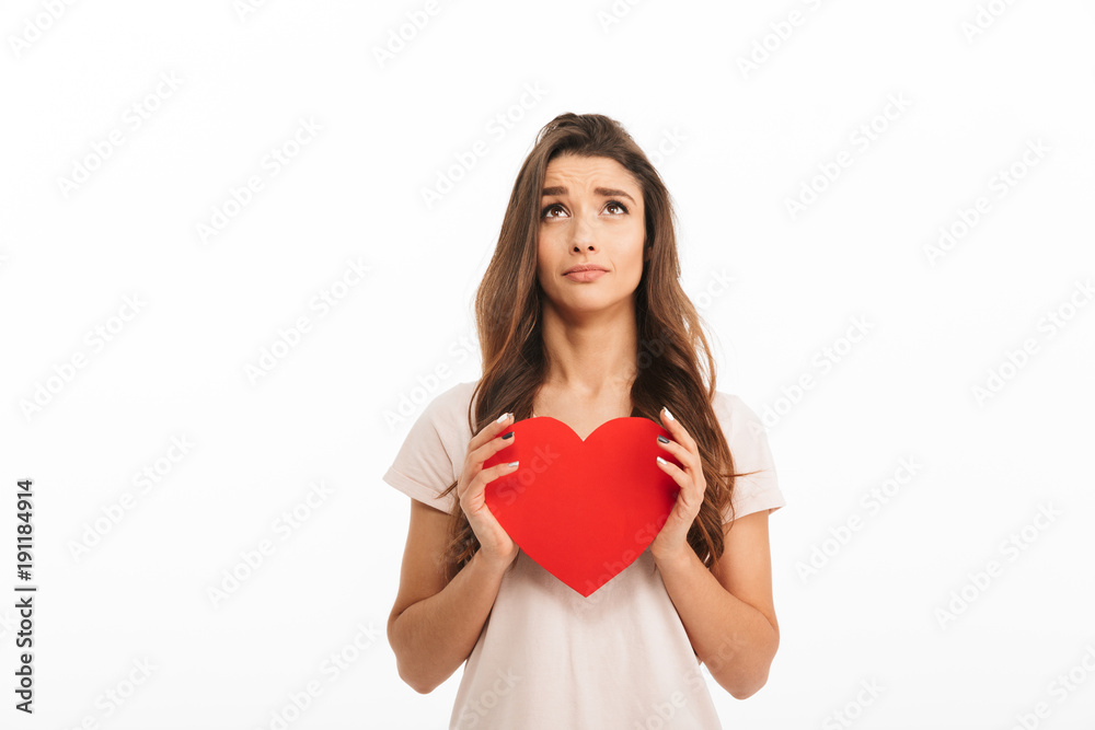 Upset woman in t-shirt holding paper heart and looking up Upset woman in t-shirt holding paper heart and looking up