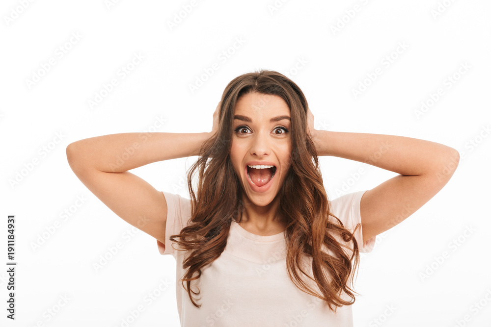 Surprised happy brunette woman in t-shirt screaming and covering ears