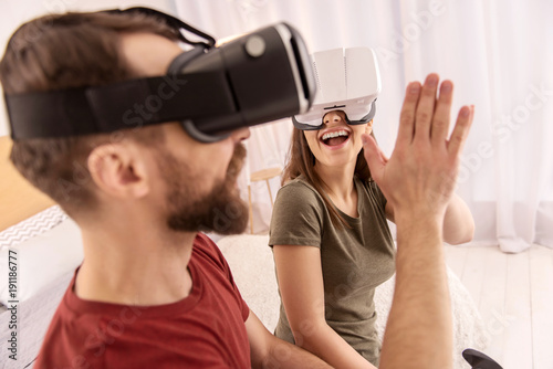 Best team. Positive joyful jolly couple exchanging high five while experiencing VR and laughing