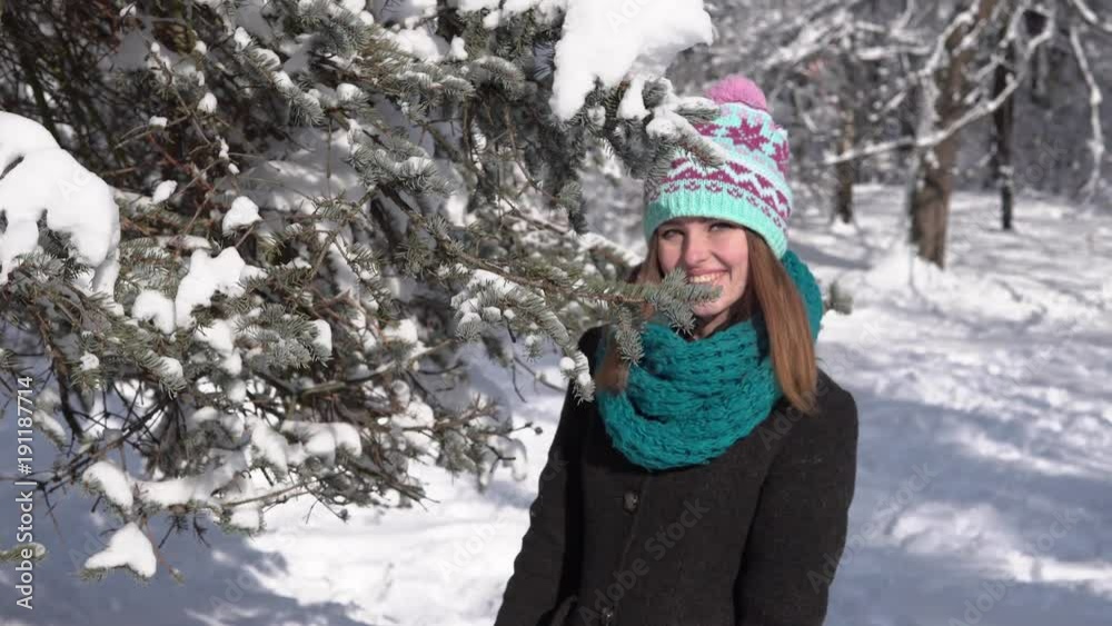 Attractive young girl having fun near snowy christmas tree in the park, outdoor sunny day Attractive young girl having fun near snowy christmas tree in the park, outdoor sunny day