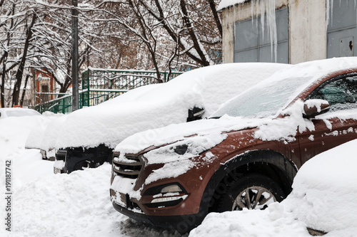 Snow covered cars on a parking near building