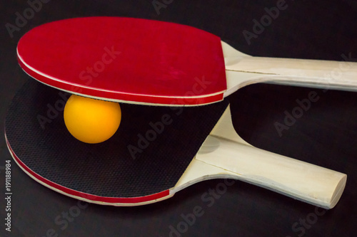Two table tennis or ping pong rackets and ball on a black background