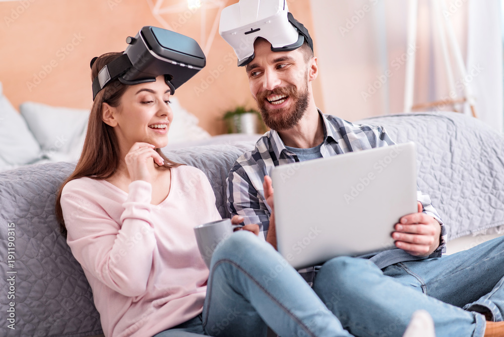 This one. Nice happy couple in VR glasses resting while bearded man grinning and carrying laptop