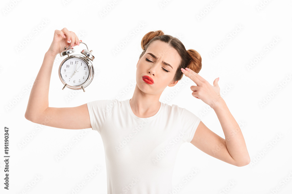 Portrait of an upset casual girl holding alarm clock Portrait of an upset casual girl holding alarm clock