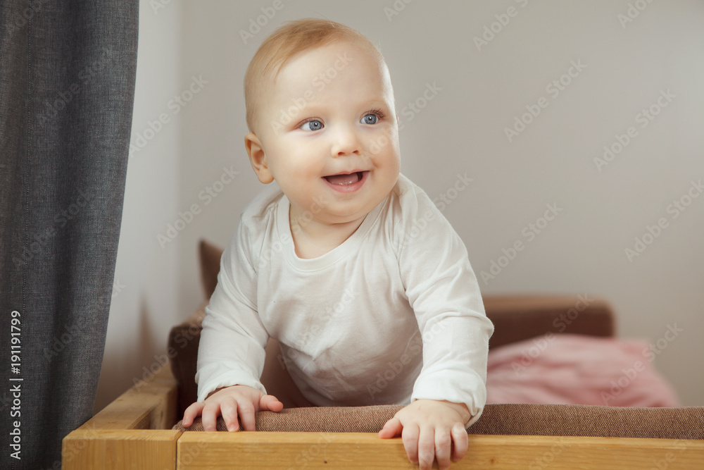 Smiling baby standing at the sofa relying on support. Smiling baby standing at the sofa relying on support.