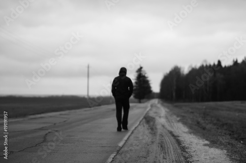 A sportsman moving away from sharpeness zone to blur on a higway in countryside landscape.
