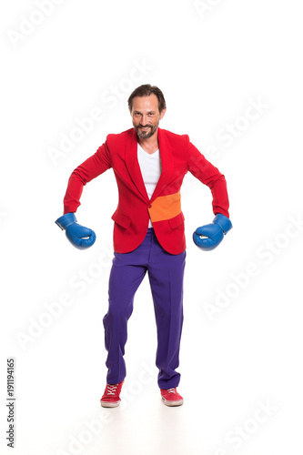 Handsome man in red jacket, purple trousers and blue boxing gloves.