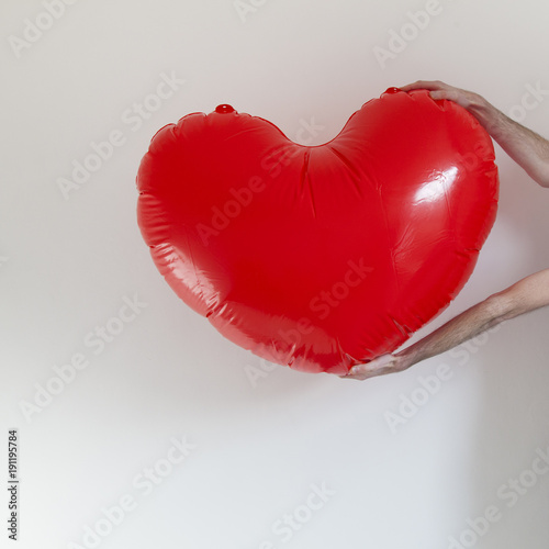 Hands holding a large inflatable heart shape photo