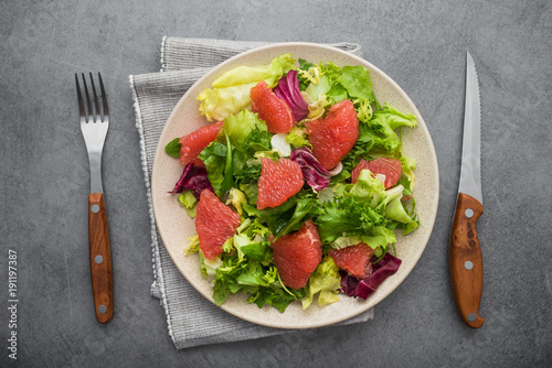 Fresh mix salad with lettuce, green arugula and sliced grapefruit in a plate