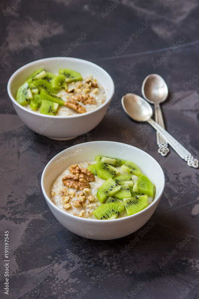 Oatmeal with kiwi fruit and walnuts. Two bowls porridge Oatmeal with kiwi fruit and walnuts. Two bowls porridge