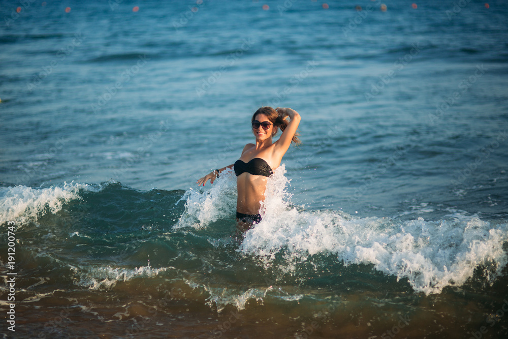 Sexy girl sunbathing on a beach and sits on the seashore Sexy girl sunbathing on a beach and sits on the seashore