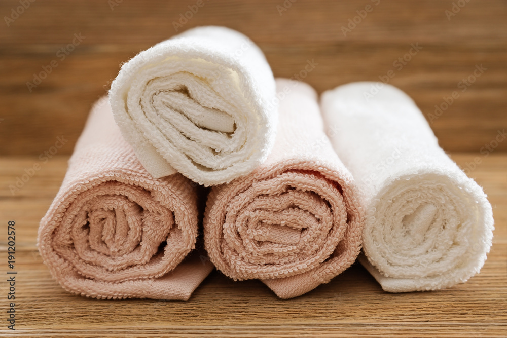 Stack of bath towels on wooden background. White and pink cotton
