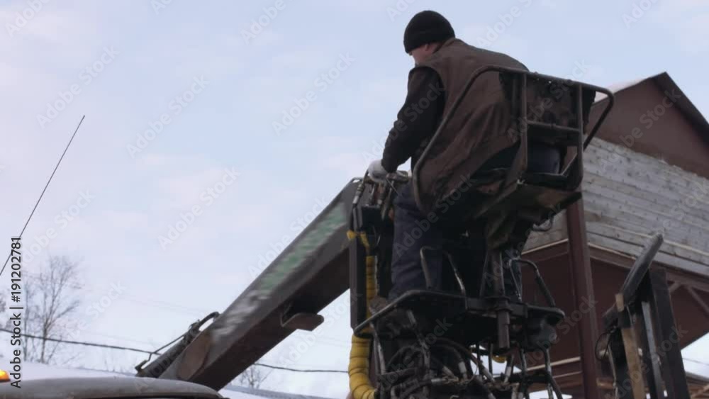 Lorry claw loader unloads timber scraps from heavy truck at sawmill facility, cold cloudy winter day