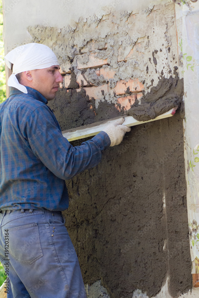 A man throws a cement mortar on a brick wall A man throws a cement mortar on a brick wall