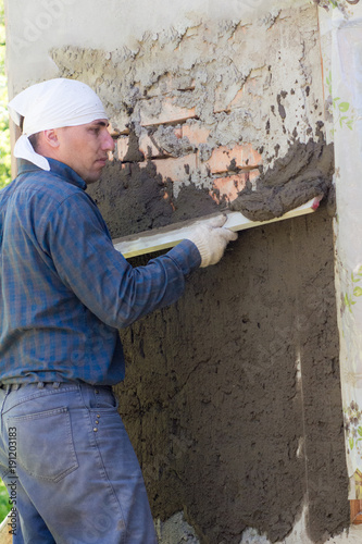 A man throws a cement mortar on a brick wall
