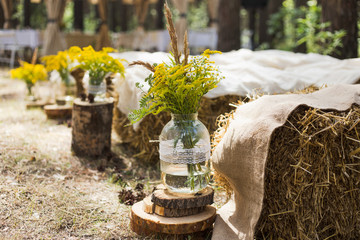 Beautifully decorated place in old autumn wood for wedding ceremony. Rustic style of elements of decor. Unusual seats made with straw. Horizontal color photography.