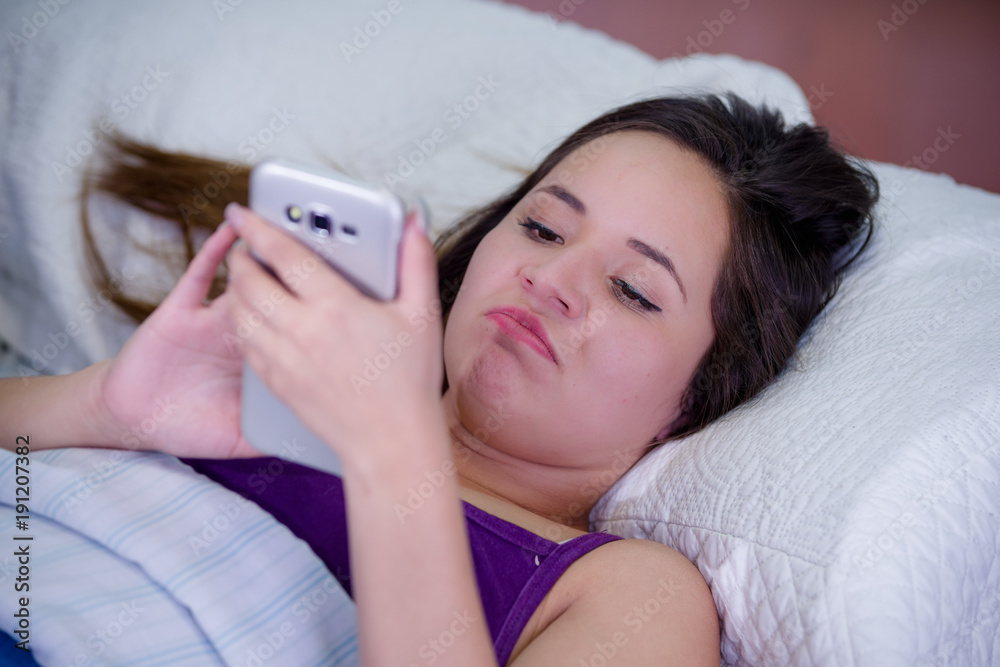 Portrait of a young woman suffering from insomnia and using her cellphone in bed Portrait of a young woman suffering from insomnia and using her cellphone in bed