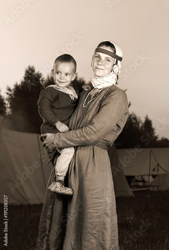 Tinted antique portrait of a slavic woman with a child in costume history. Mother and son. The image of a man from the past