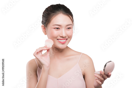 Portrait of beautiful young asian woman with perfect fresh clean skin applying cosmetic brush and use mirror.