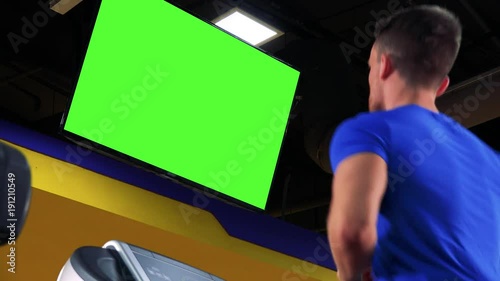 A young fit man walks on a treadmill in a gym - closeup from side
