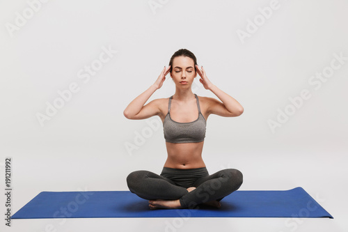 young woman meditating on yoga mat isolated on white