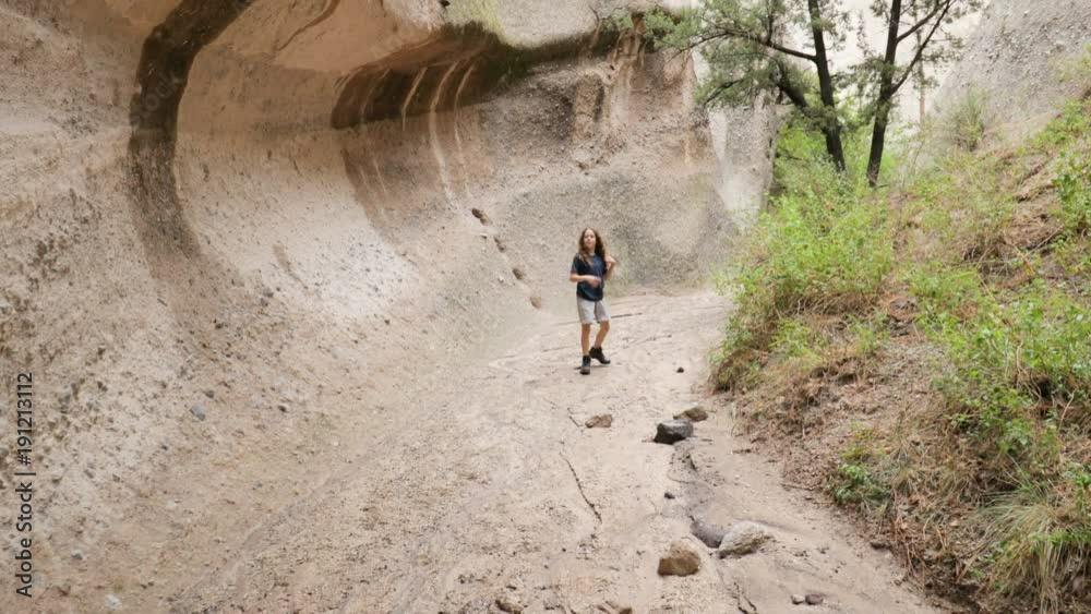 A boy running and jumping around through a slot canyon in the desert