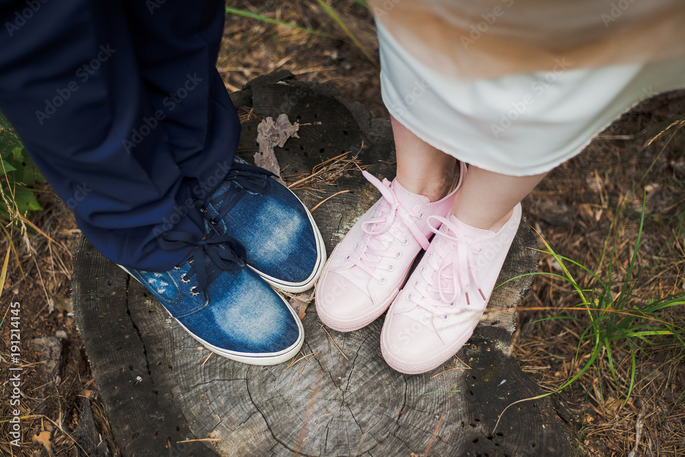 Top view of feet of cute funny wedding couple standing on old stump in  wood. Bride wearing female pink trainers shoes and groom blue sneakers.  Horizontal color photography. Stock-foto | Adobe Stock