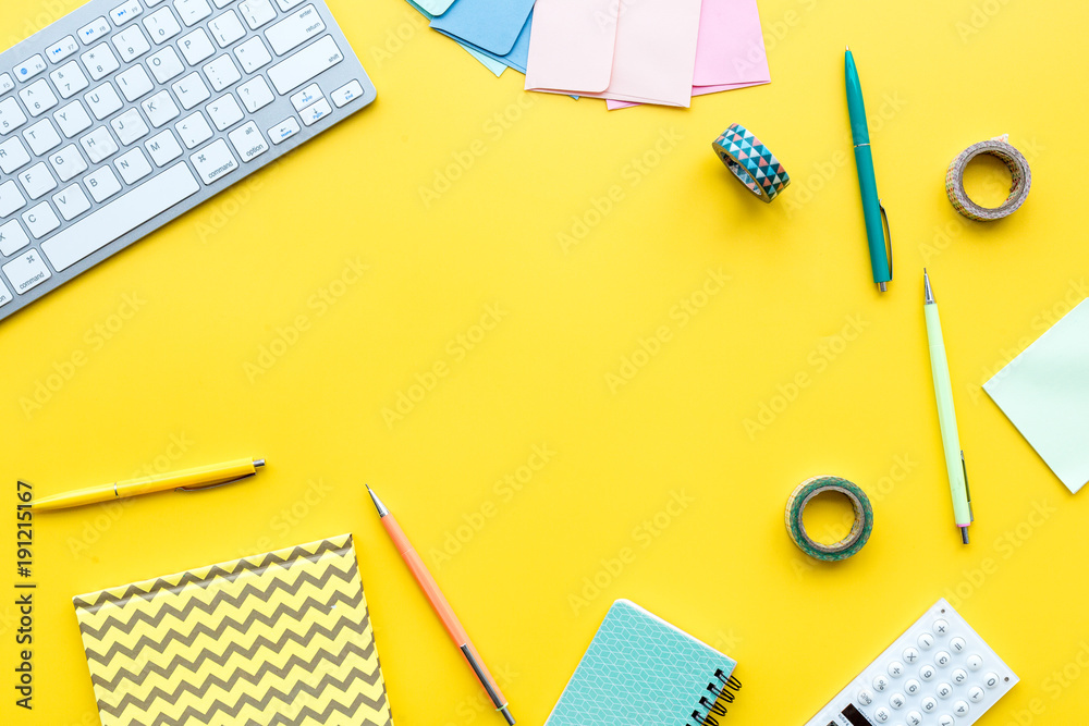 Scattered stationery near keyboard on student's desk. Yellow background top view copy space Scattered stationery near keyboard on student's desk. Yellow background top view copy space