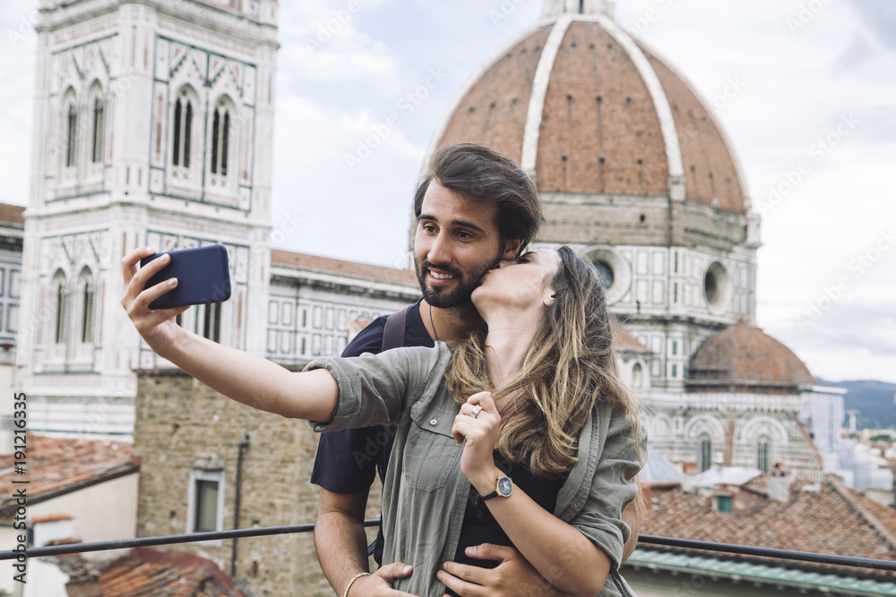 Loving couple taking a selfie in front of the church Santa Maria del Fiore, Florence Cathedral