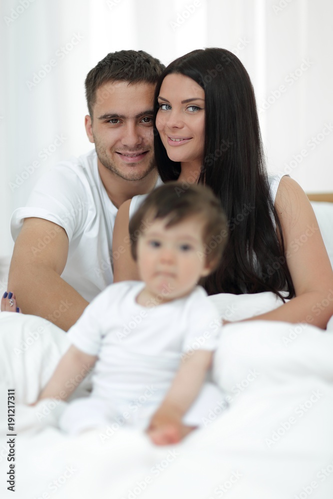 Cute little boy with parents on the bed