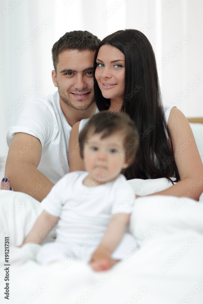 Cute little boy with parents on the bed Cute little boy with parents on the bed