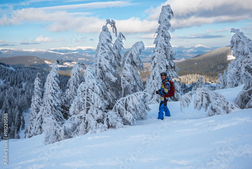 Smiling snowboarder stands among the snow-covered fir trees