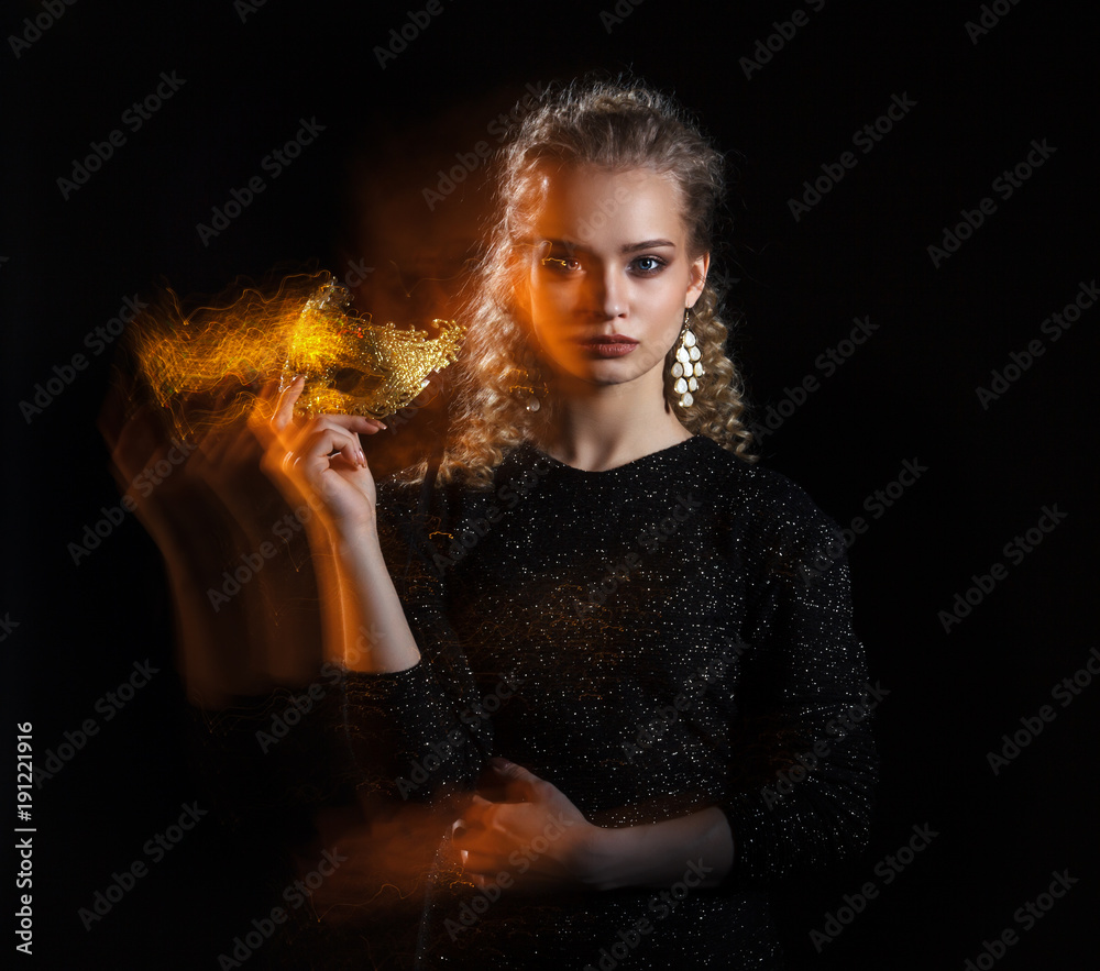 Naklejka premium Luxury young woman with a gold mask. Effect of mixed light.