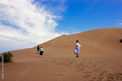 The company of tourists going to the top of the Singing Sand Dunes in Kazakhstan
