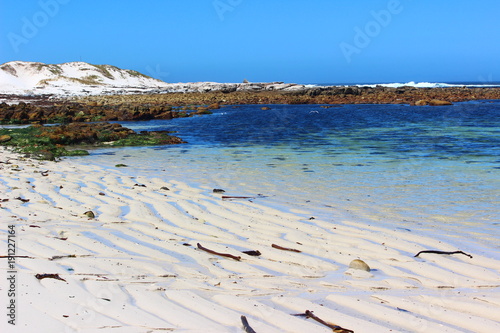 brightly blue seas and white sandy beaches with rocky shores