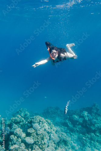 Girl in swimming mask diving in Red sea near coral reef