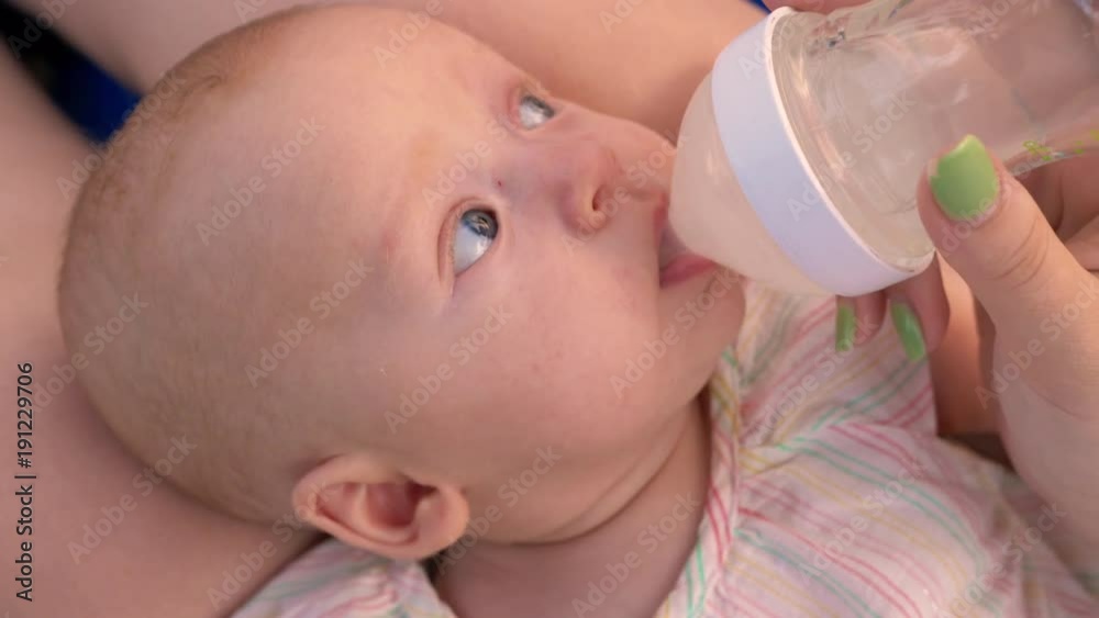 Slow motion close-up shot of three months baby girl drinking water from the bottle Slow motion close-up shot of three months baby girl drinking water from the bottle