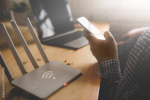 closeup of a wireless router and a man using smartphone on living room at home ofiice photo
