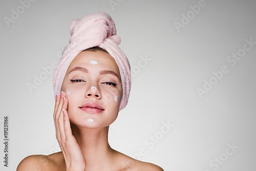 Woman with towel on her head after showering cream on face
