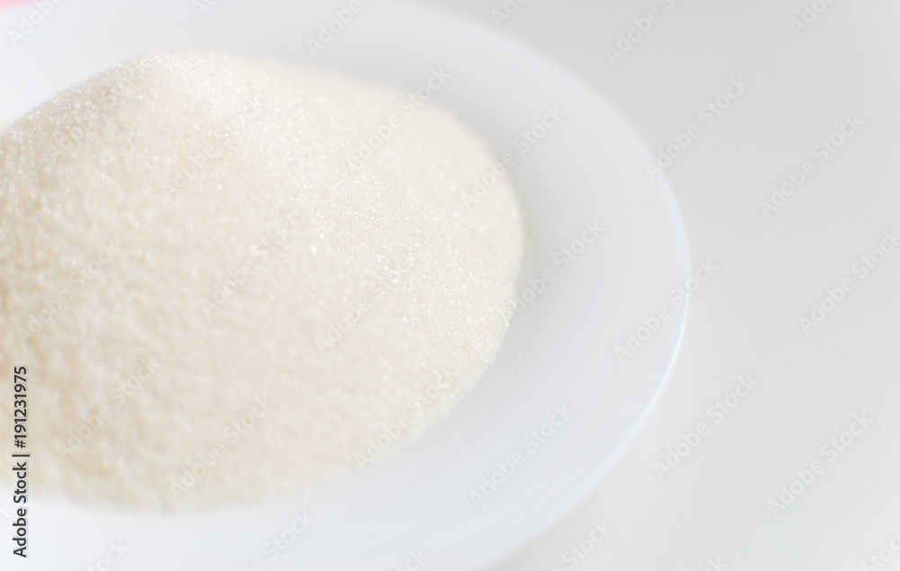 Sugar on a white plate on a white background.