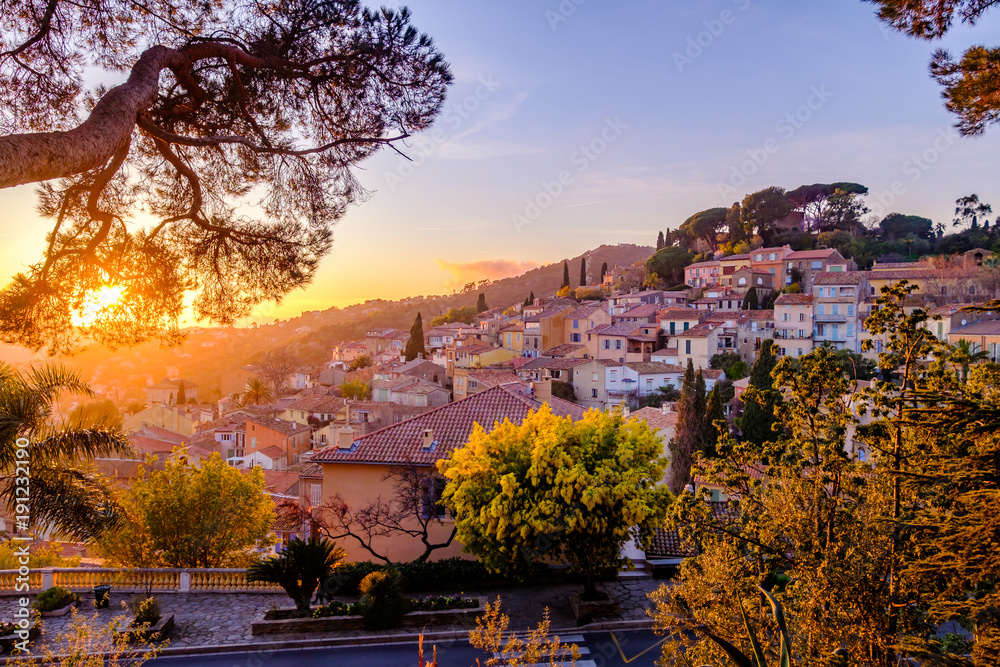 Vue panoramique sur le village de Bormes les Mimosas. Arbres de mimosa en fleurs au premier plan. Coucher de soleil. Provence, France.