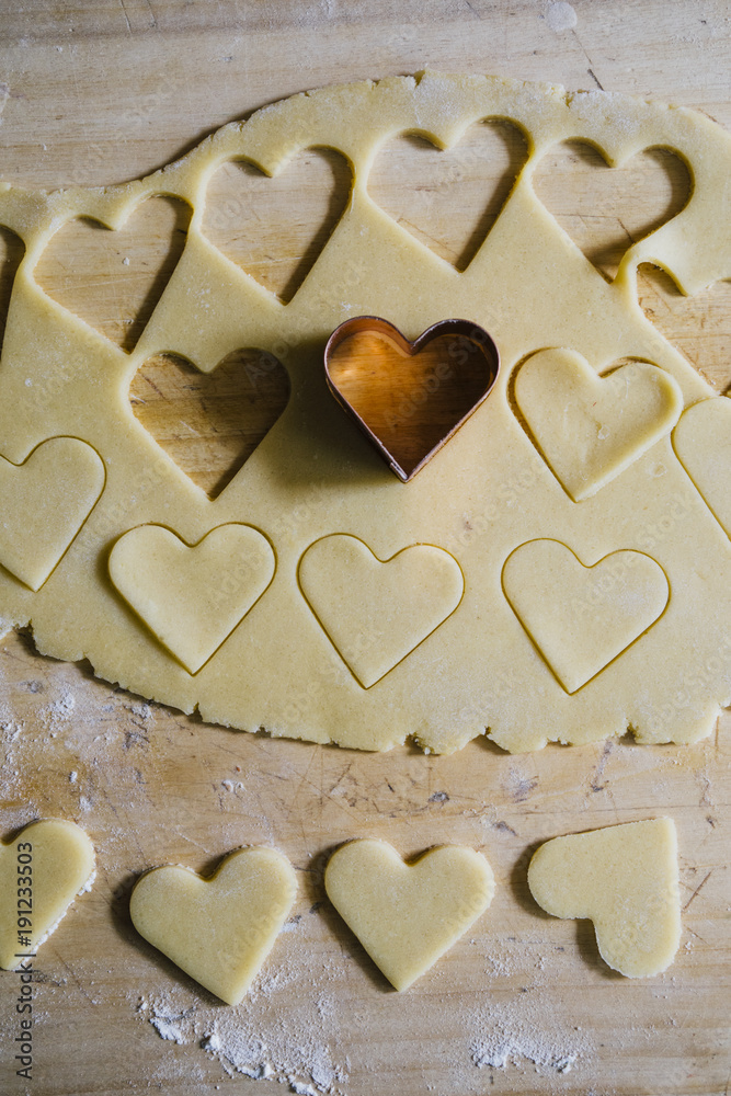 Baking Heart Shaped Cookies
for valentine's day, over a wooden  background,with cookie cutter with heart shape top view