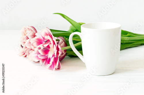 White cup mockup. Close up empty mug and tulips on wooden white background