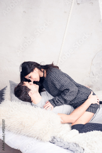 Happy Smiling Couple in love. Valentine's day. Winter portrait. Handsome young man and beautiful woman on a date spending time together at home scandinavian style.  Romance, family and love concept. 
