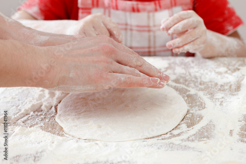 Mother and child hands prepares the dough with flour for bread or pizza. Bakery background.