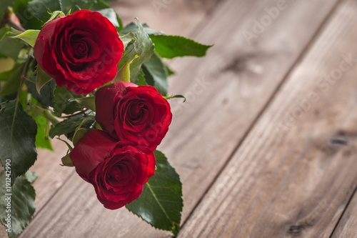 Red roses on the wooden background   place for a text