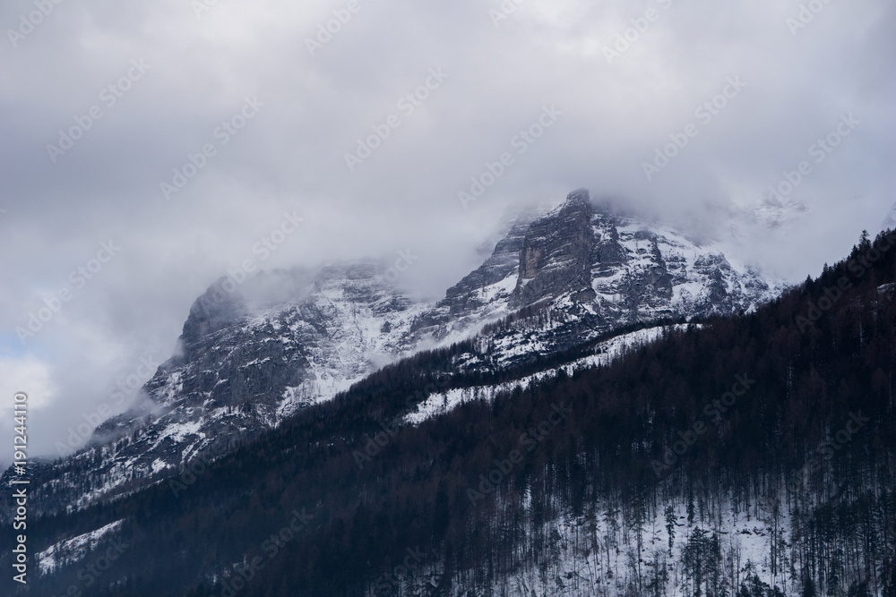 Obraz premium Spooky mountains scenery with alpine peak shrouded in fog and clouds