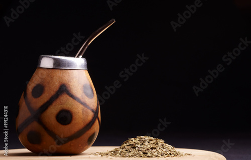 Traditional South American yerba mate tea in the calabash circle and Bombilla. Black background photo